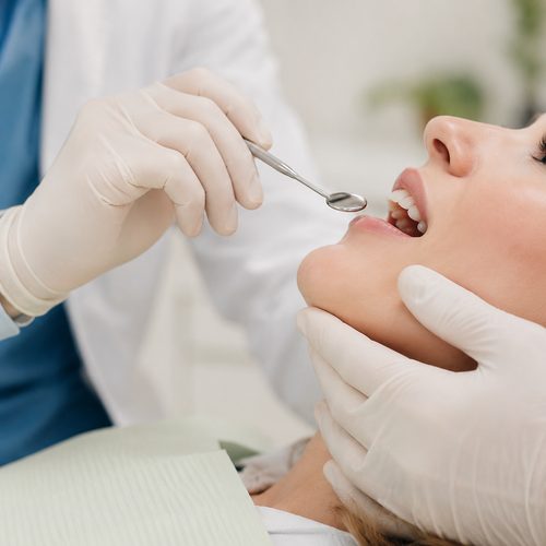 Dentist examining a patient's mouth with a mirror